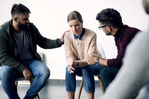young-sad-woman-being-consoled-group-therapy-counselling-scaled.jpg